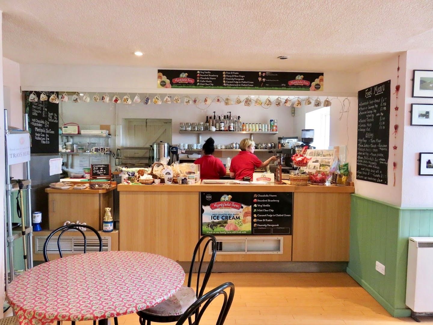 Inside Caen Hill Cafe: a wooden counter with chalkboard menus, an ice cream sign and a small table with a red spotted cloth